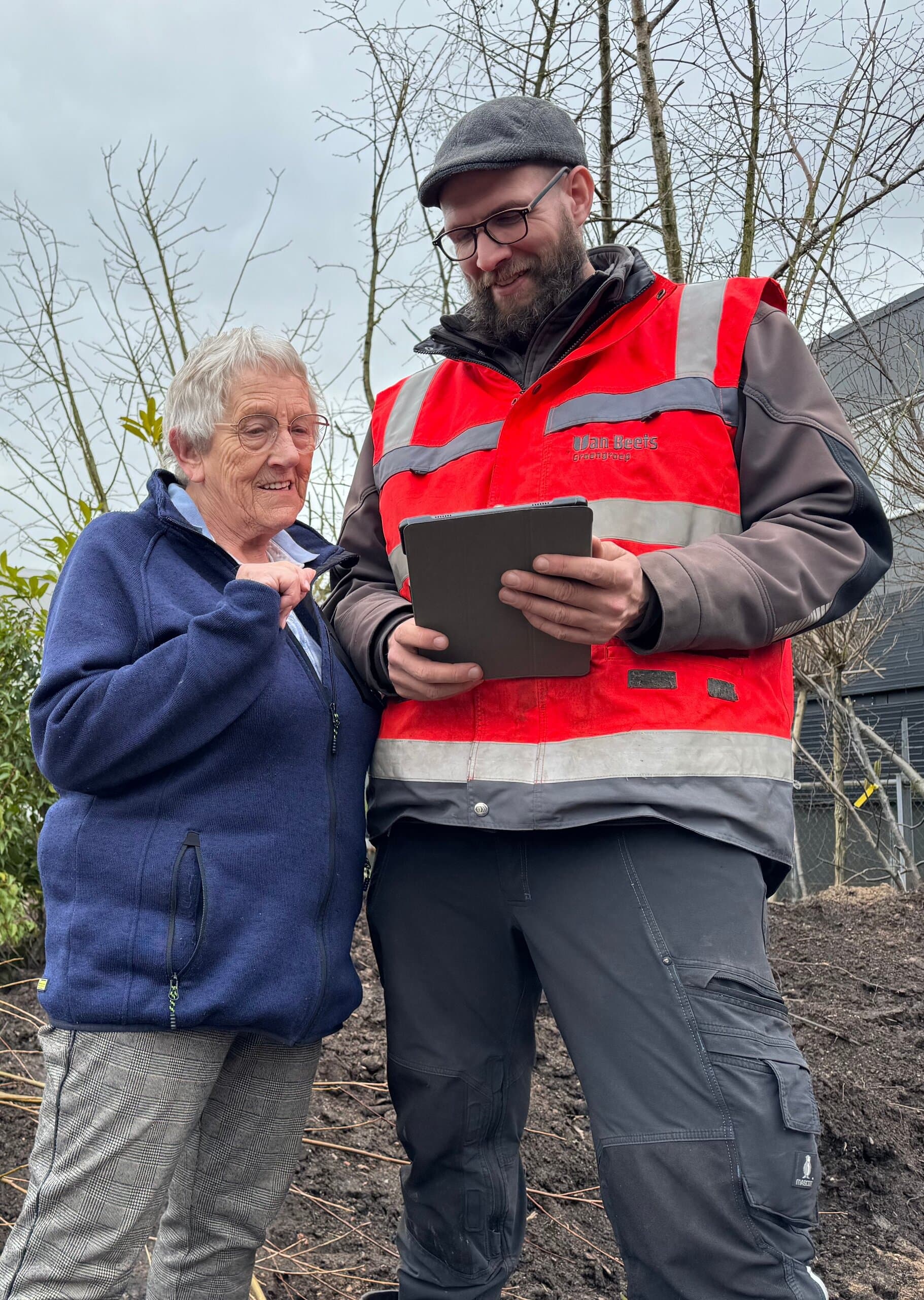 Een hovenier van Van Beets laat een klant op een tablet zien wat er in haar tuin gaat gebeuren