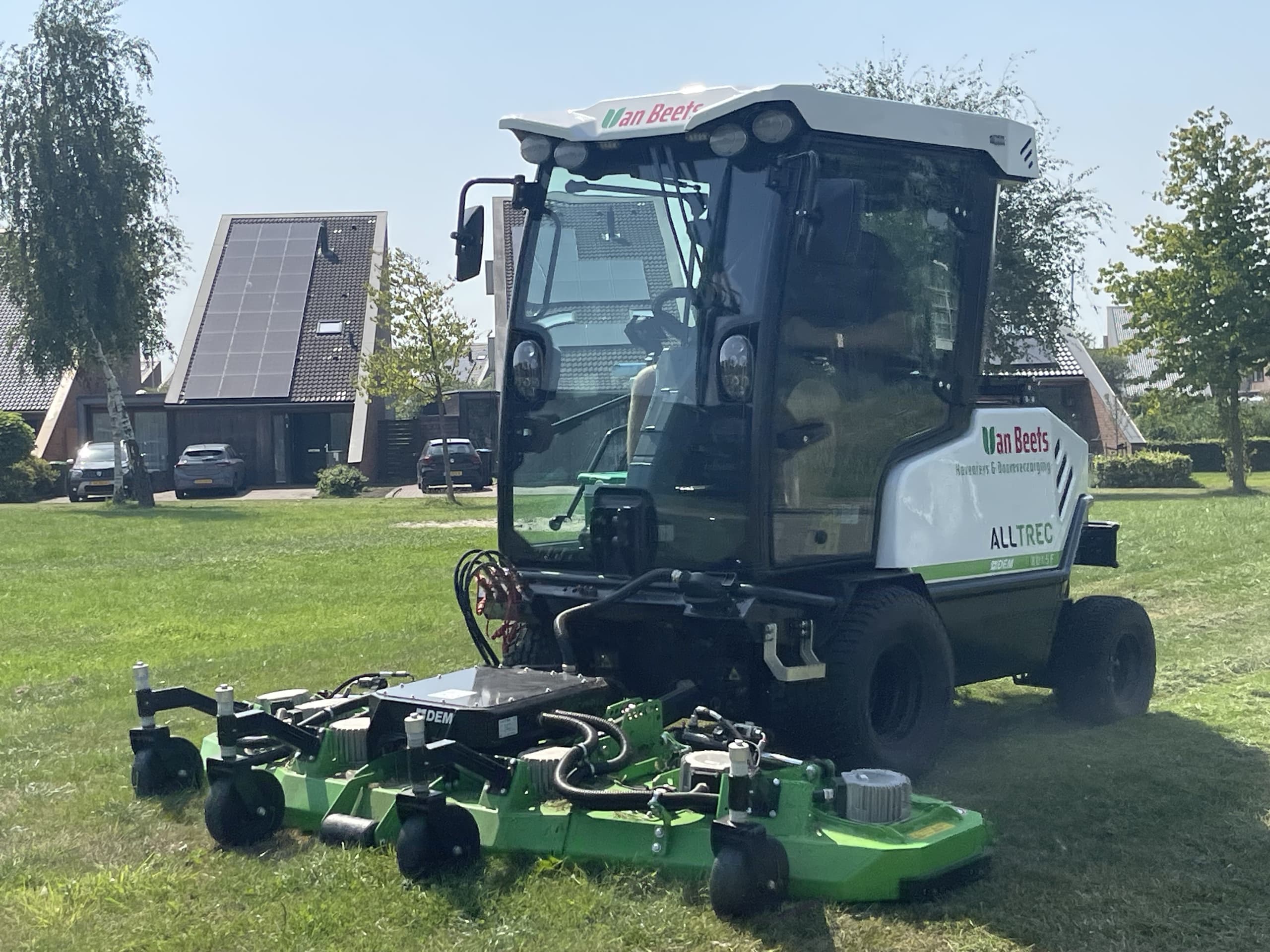 Volledig elektrische maaimachine van Van Beets van dichtbij, met groene maaidekken, aan het werk op een grasveld in een woonwijk
